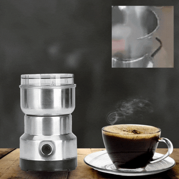ForKumi small electric grinder for home made of stainless steel next to a steaming cup of coffee on wooden table