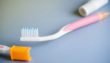 Close-up of a pink and white kids toothbrush with blue bristles, illustrating safe kids toothbrushes 2025