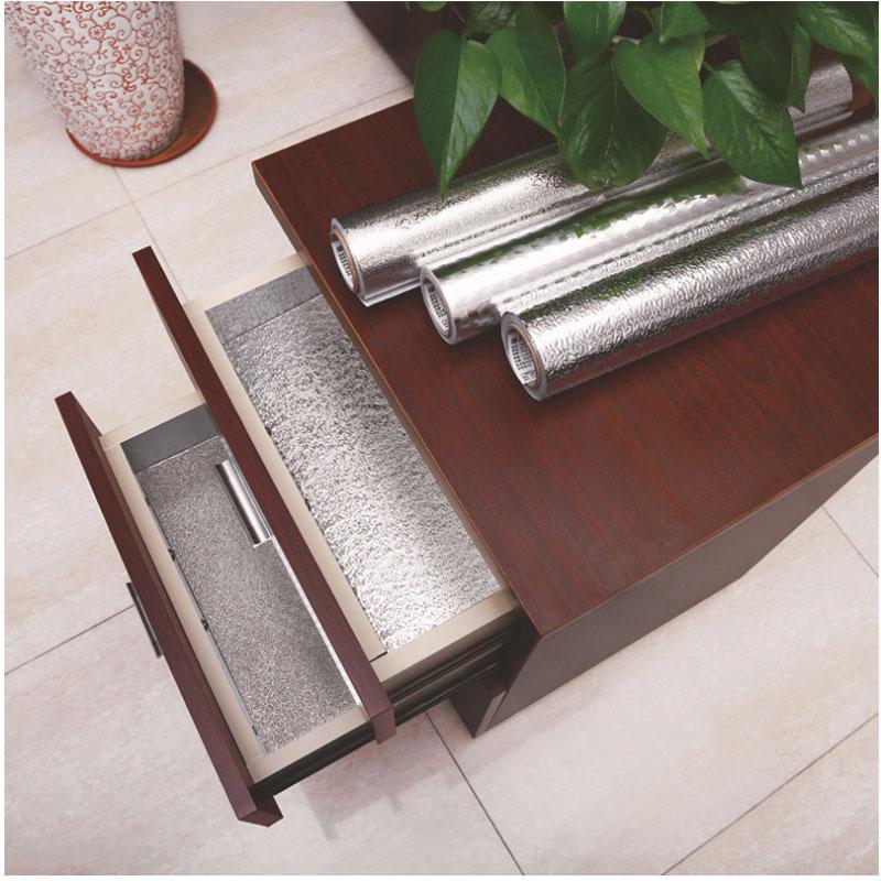 ForKumi aluminum foil kitchen sticker rolls displayed on a wooden table with one applied inside a drawer for protection