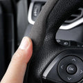 ForKumi black anti-slip steering wheel cover showing textured grip with hand on car steering wheel