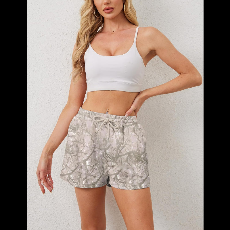 Woman wearing Avis camo elastic waist shorts with white crop top against white wall