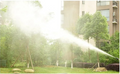 ForKumi 1400W electric pressure washer spraying water in a garden near residential buildings