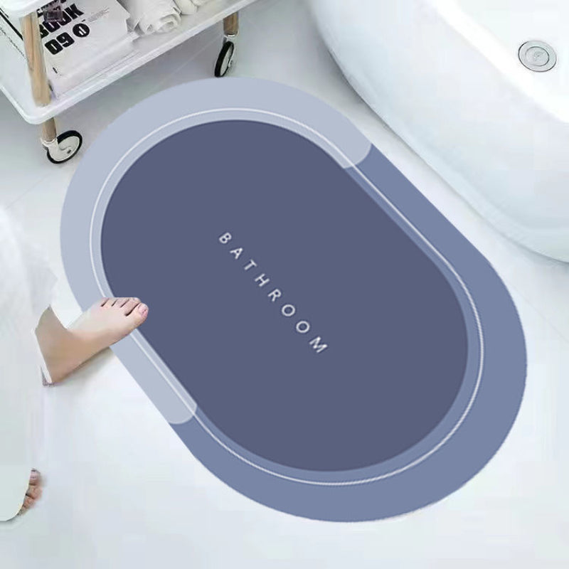 ForKumi quick dry bath mat in gray blue with oval shape placed next to bathtub on white bathroom floor