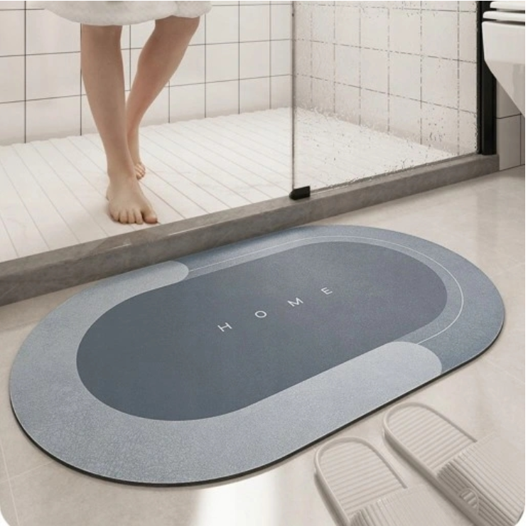 ForKumi quick dry bath mat in blue and gray with HOME text placed outside shower door on bathroom floor