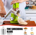 ForKumi 3-blade vegetable slicer shredding nuts into a glass bowl with a green base and hand-operated crank
