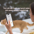 Person checking water quality on phone app for cat water dispenser with TDS monitor with cat drinking in background