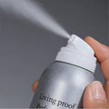 Hand spraying silver can of MIT dry shampoo spray releasing mist for quick hair refresh