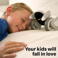 Child resting next to Loona AI robot pet on bed showing interactive AI toy for kids
