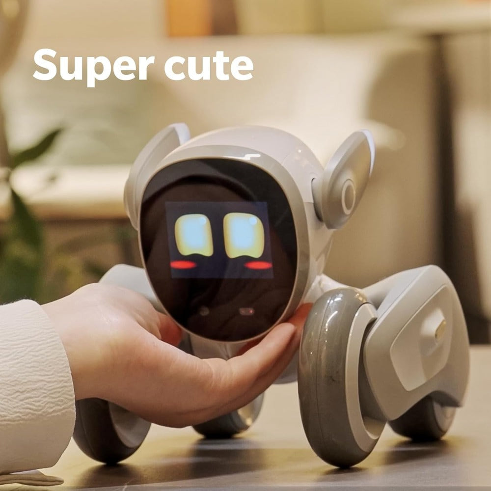 Loona AI robot pet with digital face being held by a hand on a table in a cozy room