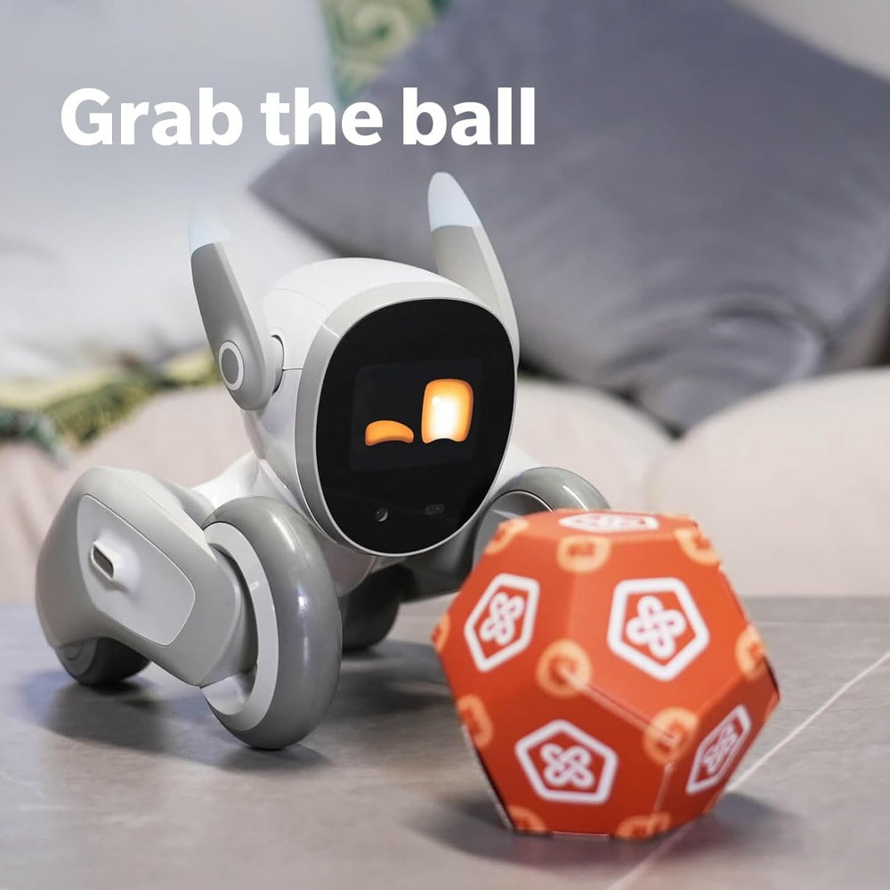 Loona AI robot pet on wheels interacting with an orange toy ball on a table in a cozy room