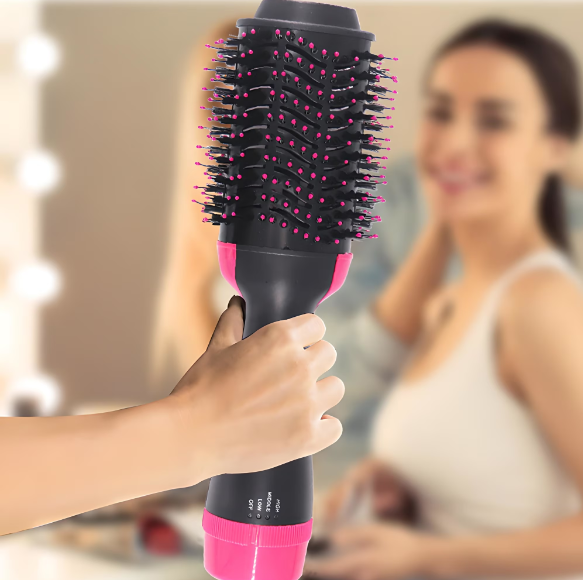 ForKumi 1000W hot air brush styler held in hand with black and pink bristles and blurred background