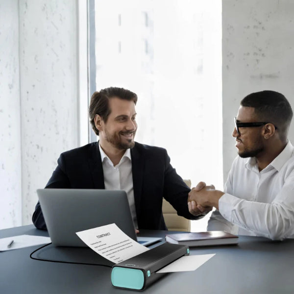 Two businessmen shaking hands with a portable thermal printer printing a document on the table
