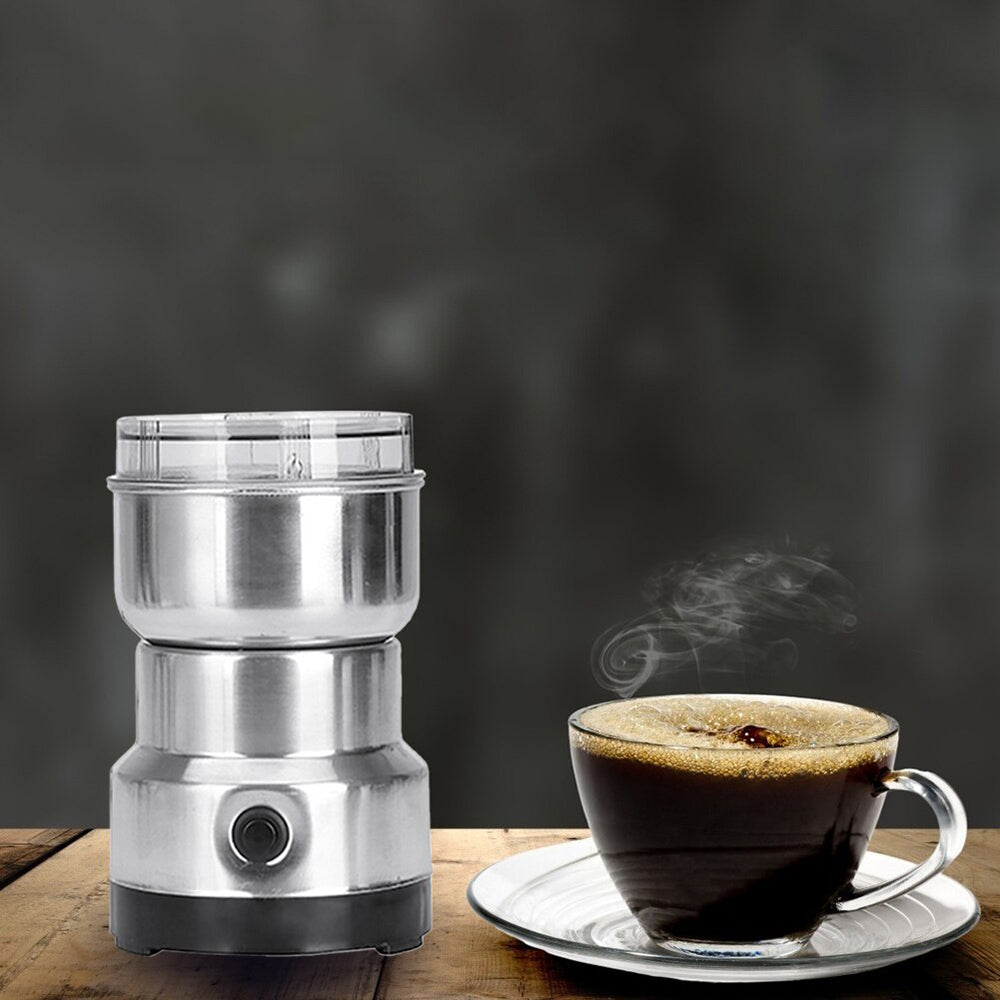 ForKumi small electric grinder for home made of stainless steel next to a steaming cup of coffee