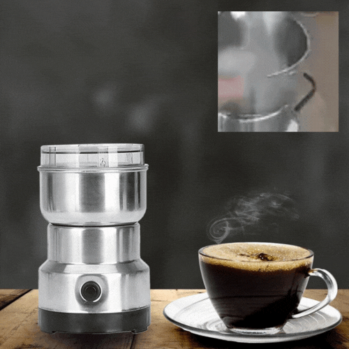 ForKumi small electric grinder for home made of stainless steel next to a steaming cup of coffee on wooden table