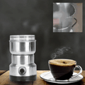 ForKumi small electric grinder for home made of stainless steel next to a steaming cup of coffee on wooden table