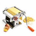 ForKumi stainless steel pasta maker with orange handle rolling fresh pasta dough next to eggs and flour