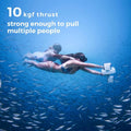 Underwater scooter for adults being used by two swimmers surrounded by fish in clear blue water
