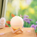 ForKumi ultrasonic humidifier with essential oils emits mist from round white diffuser on wooden stand