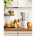 Avis USB-C cordless citrus juicer on kitchen counter with fresh fruit and glass of juice