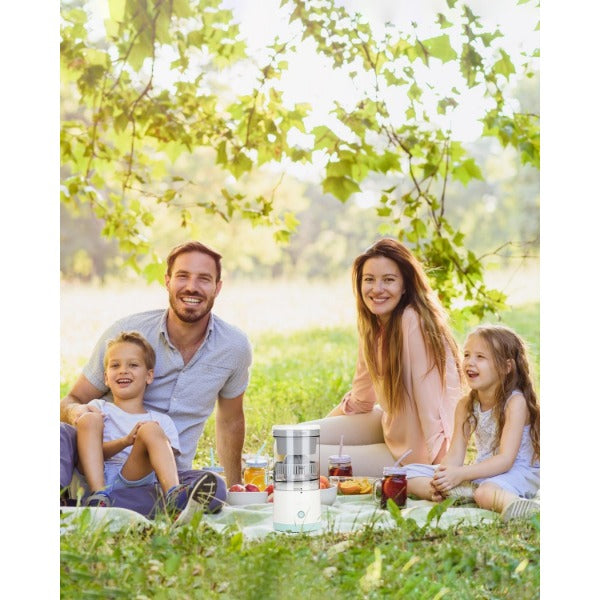Avis USB-C cordless citrus juicer on picnic blanket with family enjoying outdoor gathering