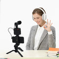 Woman using vlog creator kit with microphone and smartphone on tripod while wearing headphones